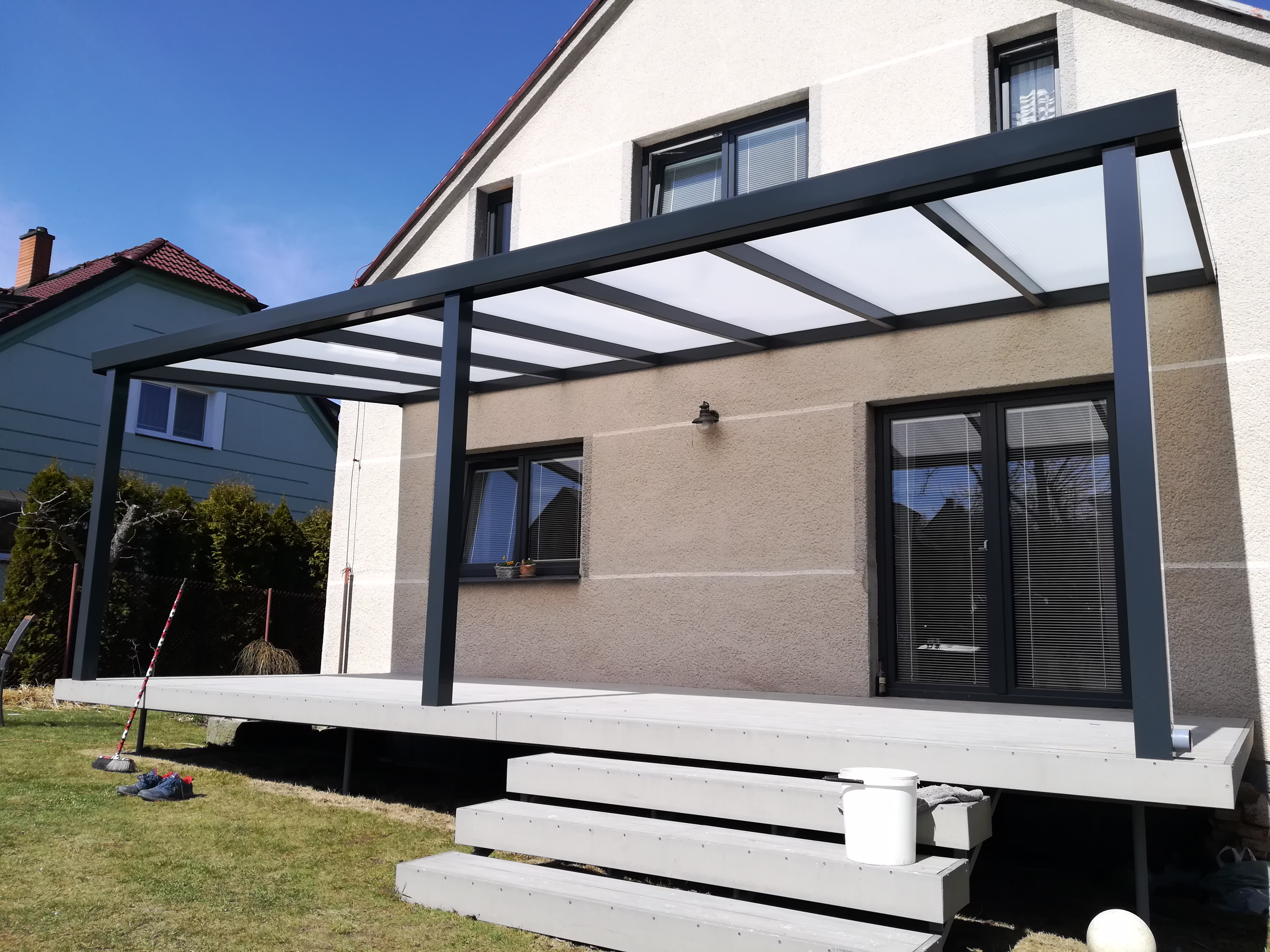 antracitová pergola s opálovou střechou nad šedou terasou