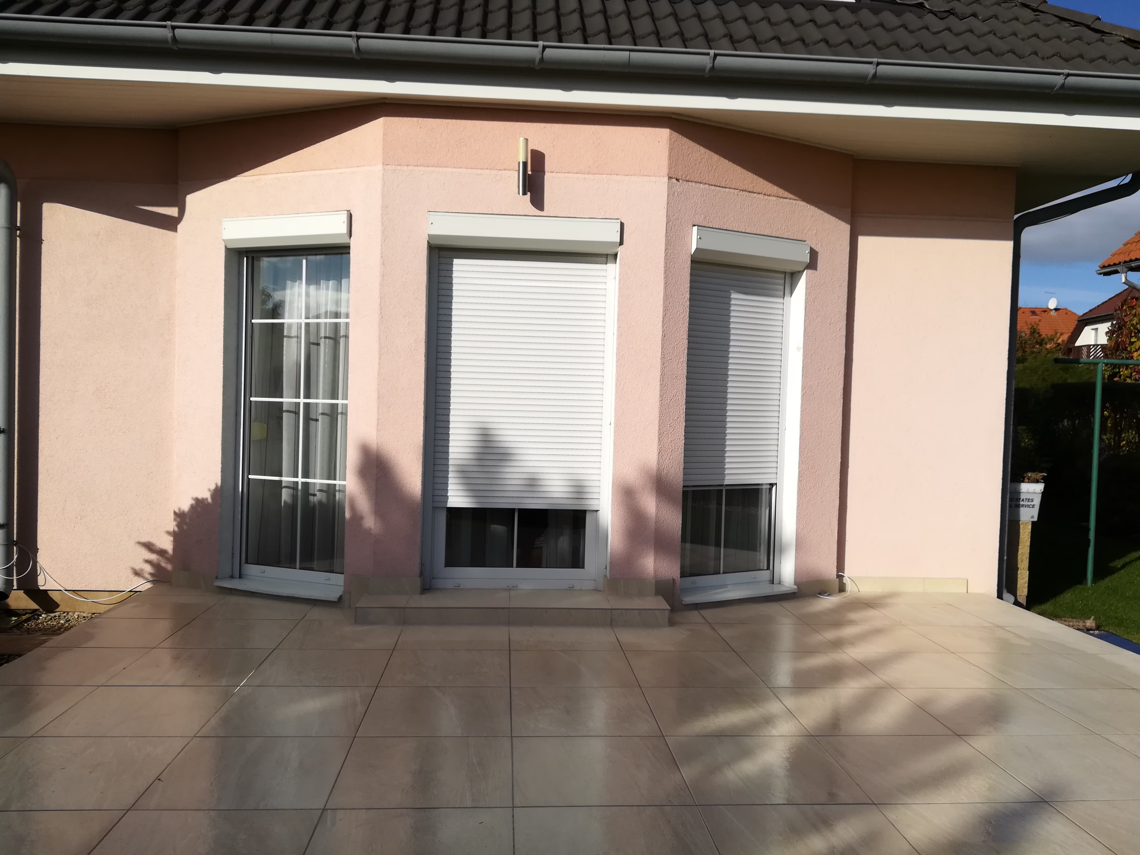 holá béžová dlažba u meruňkového domu s arkýřovými okny
