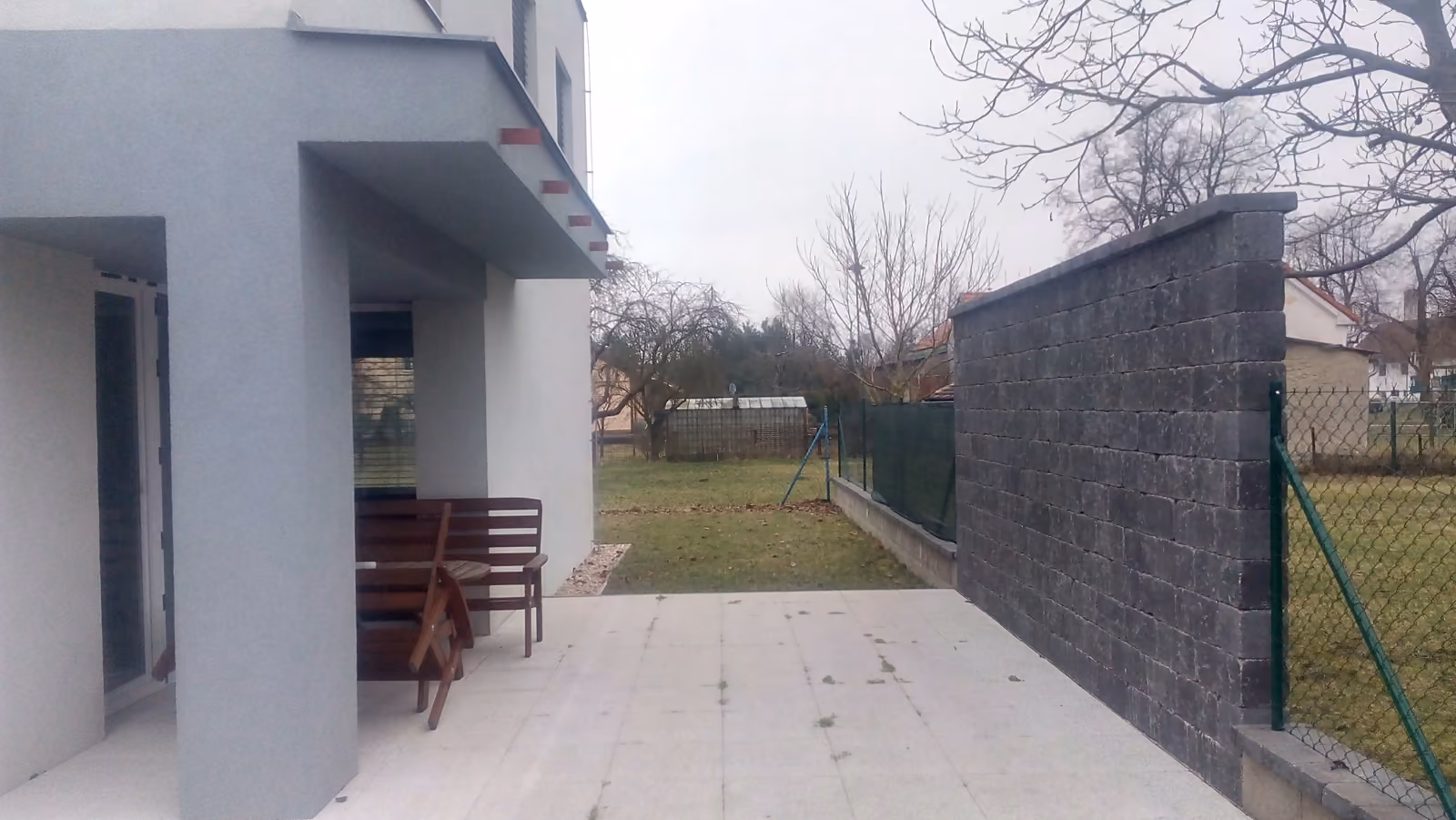 holá šedá dlažba vedle stěny z tmavých bloků