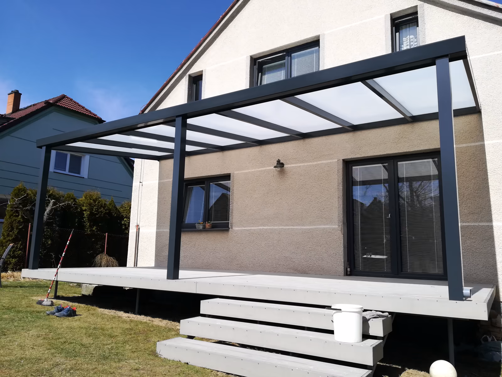 antracitová pergola s opálovou střechou nad šedou terasou